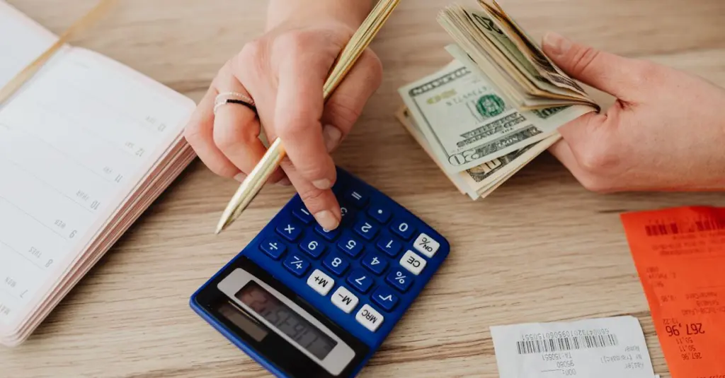 Manos con calculadora y dinero haciendo cuentas de presupuesto