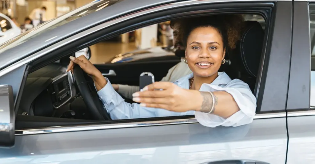 Mujer sonriente sentada en su auto sosteniendo las llaves