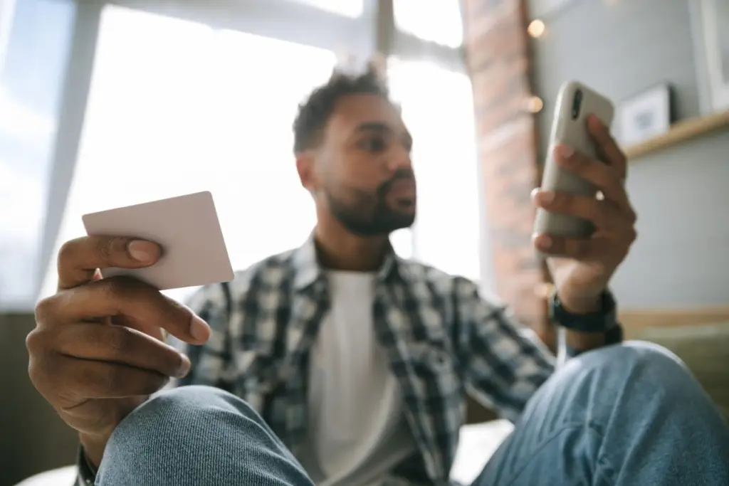 Persona usando su telefono y una tarjeta para enviar y recibir dinero