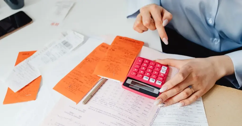 Persona calculando ingresos con recibos y calculadora