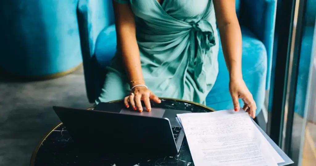 Mujer comparando documentos financieros en laptop