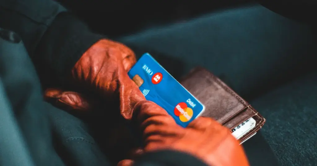 Persona sosteniendo tarjeta de crédito y billetera