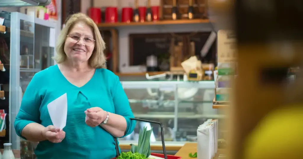 Mujer revisando recibo de compra con bolsas del mercado