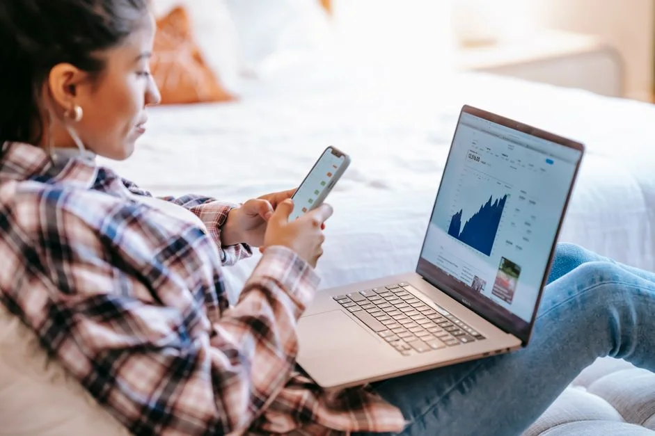 Mujer revisando sus finanzas en el celular y el computador