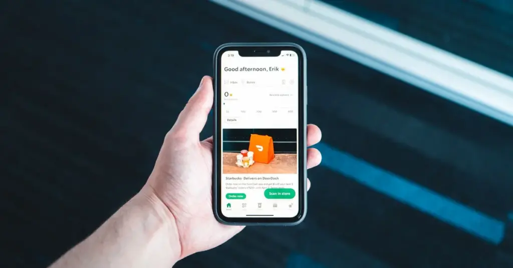 Mano sosteniendo un celular con una app de delivery abierta