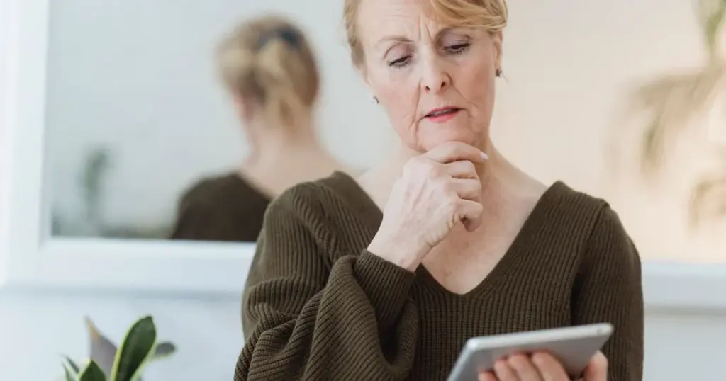 Mujer esceptica mirando la pantalla de su celular con desconfianza