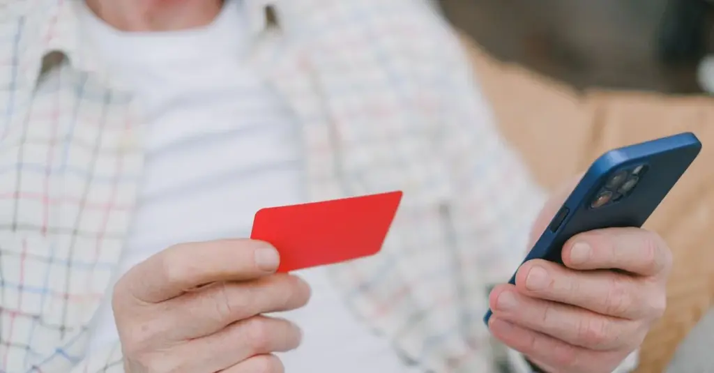Persona usando tarjeta y celular para un pago en línea