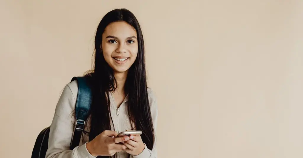 Estudiante adolescente con mochila usando su celular