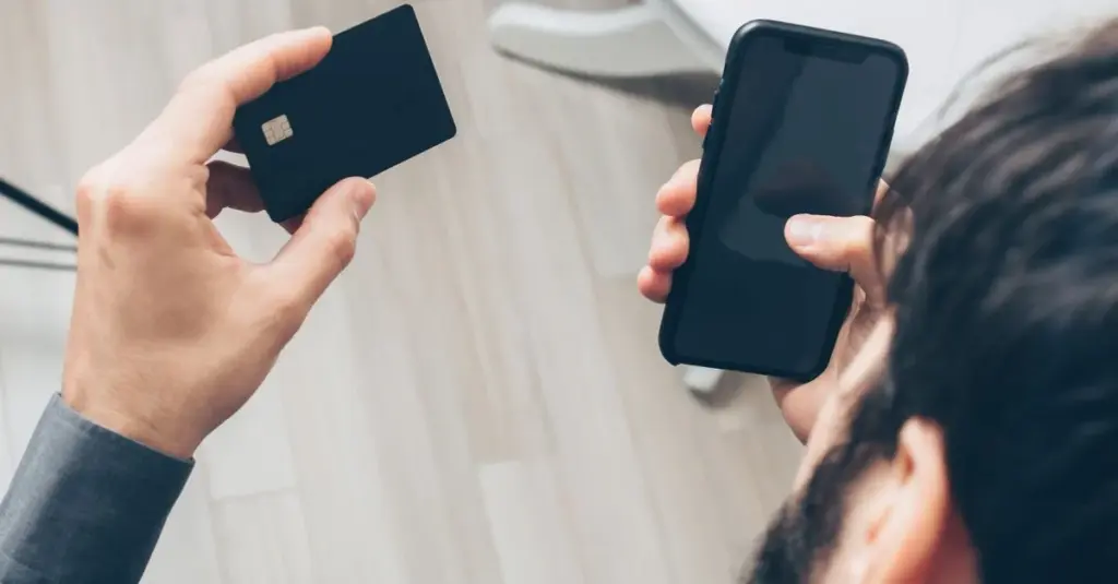Hombre sosteniendo smartphone y tarjeta para pago automático