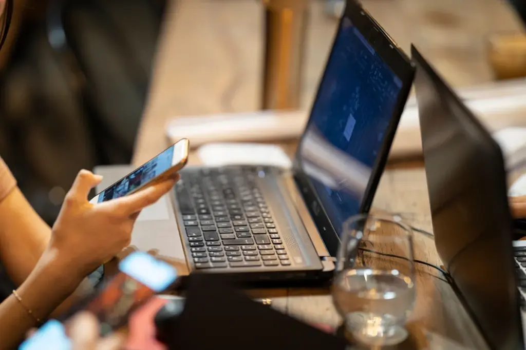 Persona comparando opciones en laptop y celular
