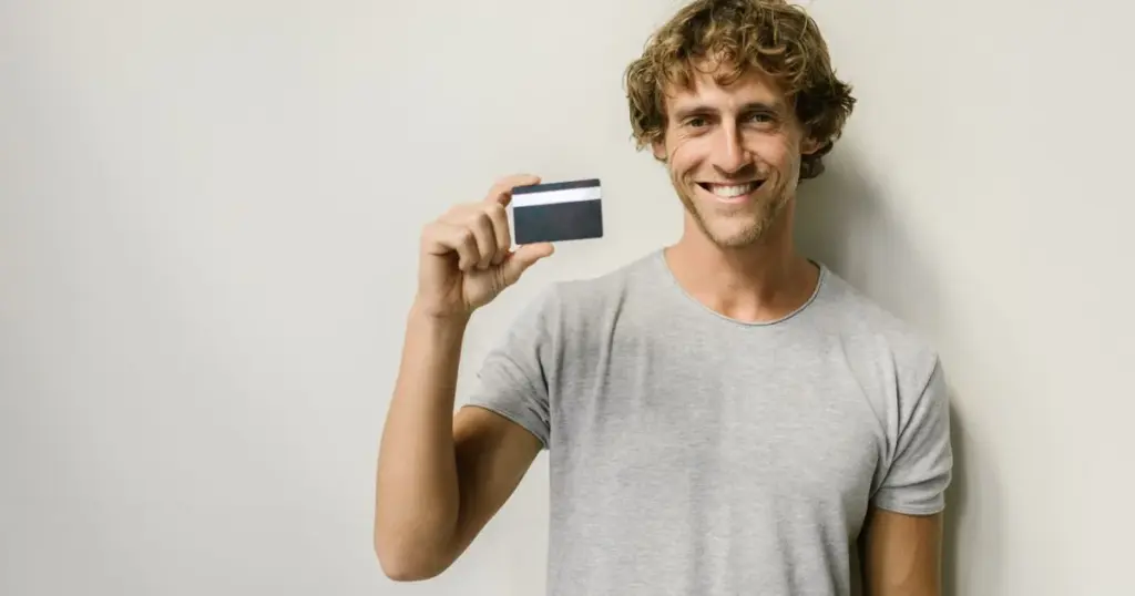 Hombre sonriente mostrando una tarjeta bancaria