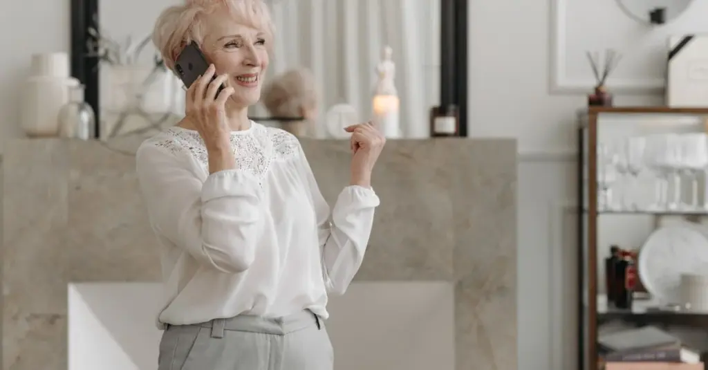 Mujer mayor hablando por teléfono en su sala