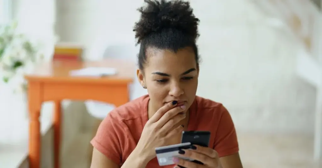 Joven usando su celular y tarjeta para compra en línea