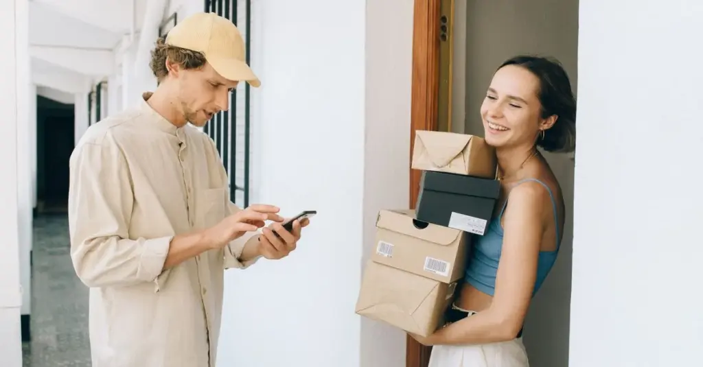 Mujer recibiendo un paquete y pagando con celular