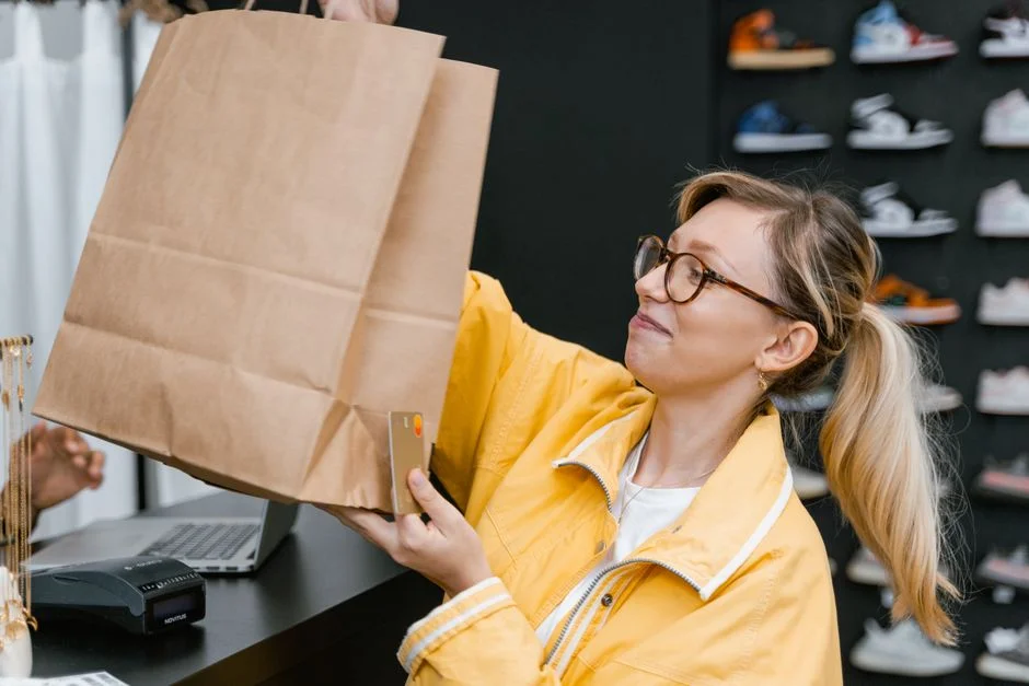 Mujer con bolsa de compras sosteniendo una tarjeta en una tienda