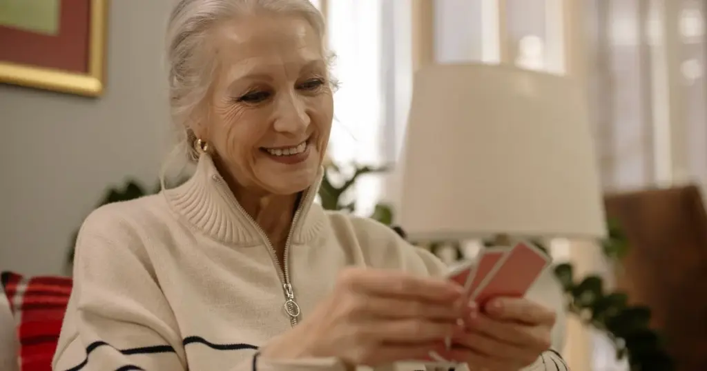 Mujer mayor sonriendo mientras sostiene tarjetas en la mano