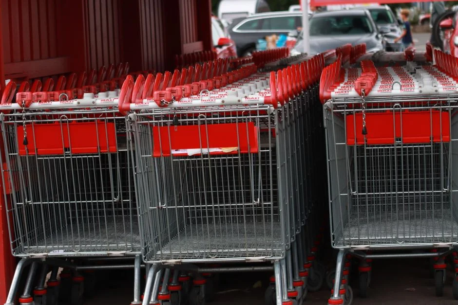Fila de carritos de compras metálicos rojos en un estacionamiento