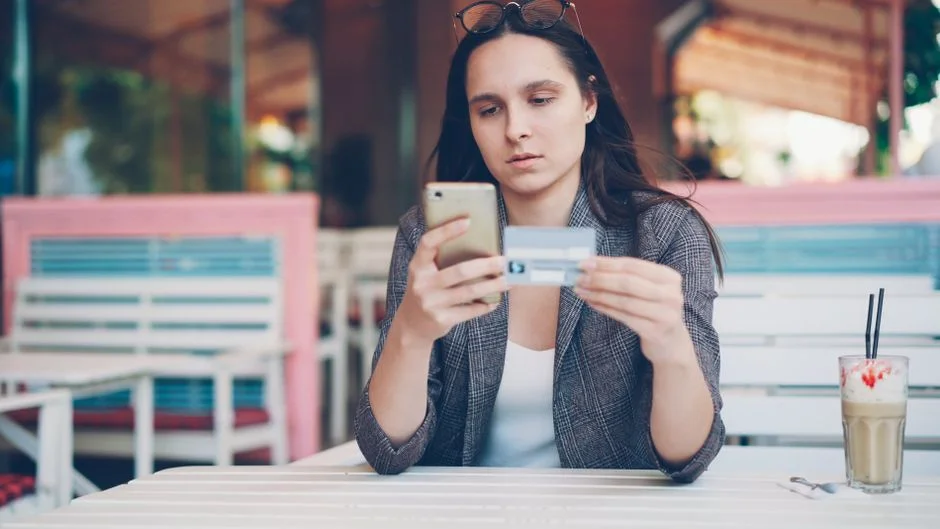 Mujer usando el celular y una tarjeta para comprar en línea