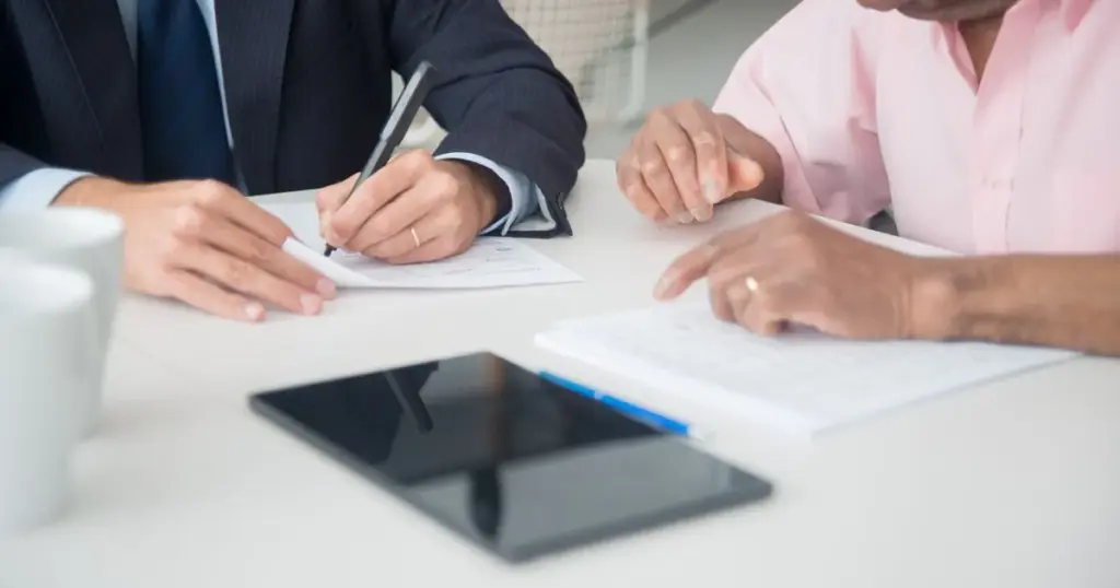 Dos personas revisando y firmando documentos de un contrato financiero