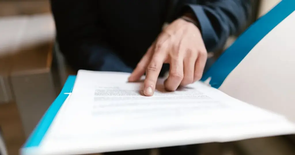 Mano señalando la letra pequeña de un contrato impreso