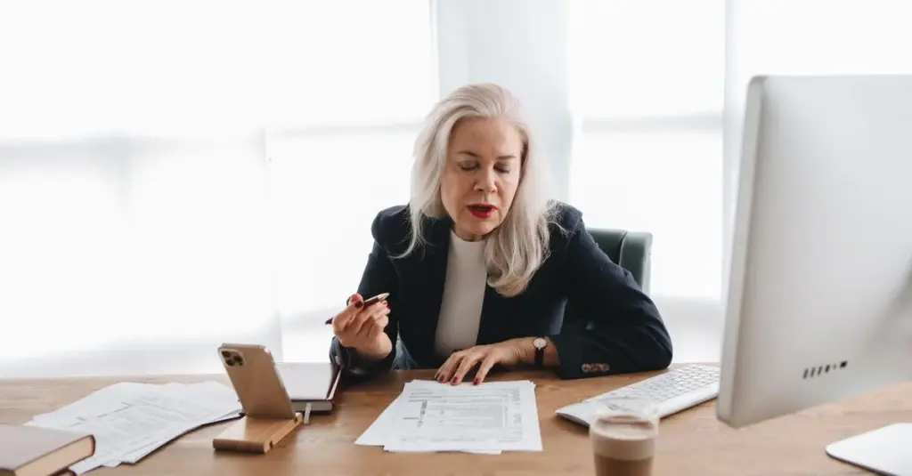 Mujer mayor revisando documentos financieros en la oficina