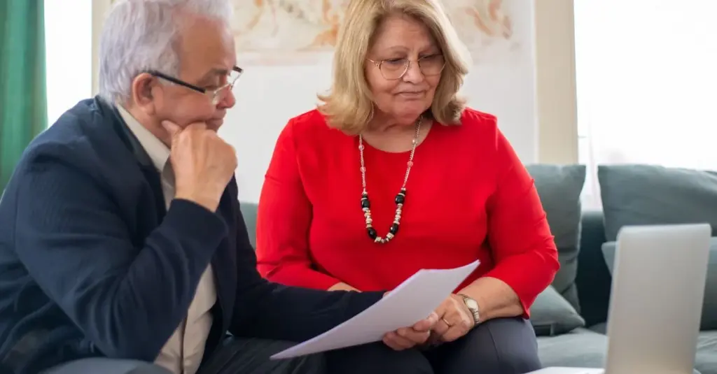 Pareja mayor revisando documentos financieros juntos en casa