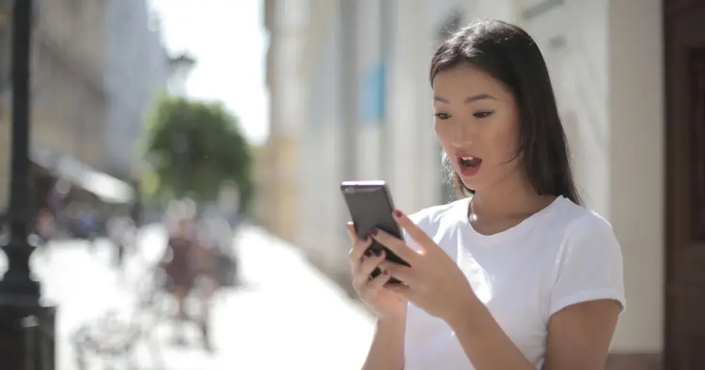 Mujer sorprendida mirando la pantalla de su celular