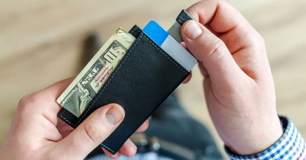 Manos sosteniendo una cartera con efectivo y tarjetas