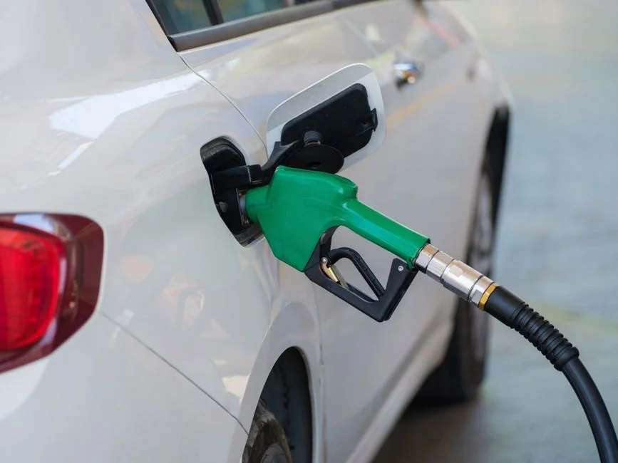 Persona llenando el tanque de gasolina en una estación de servicio