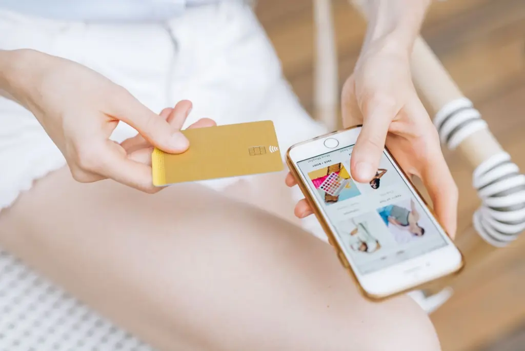 Mujer sosteniendo un celular y una tarjeta de crédito