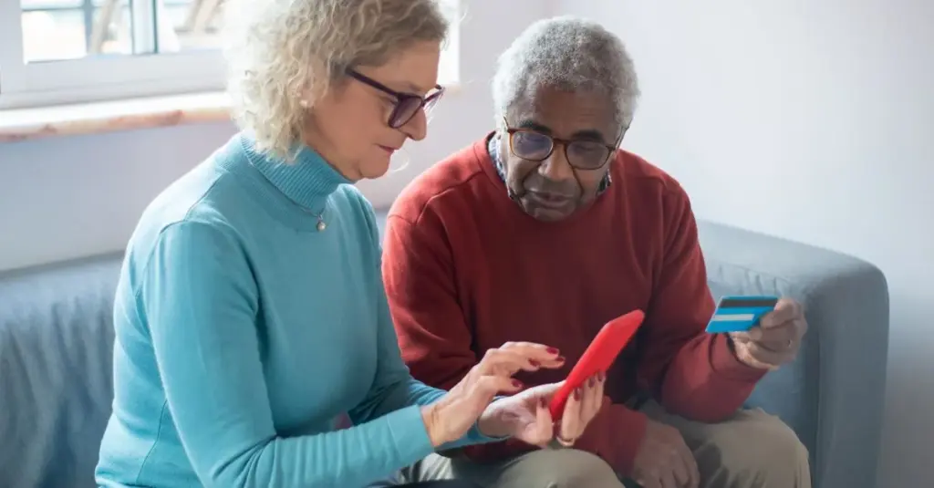 Pareja de adultos mayores usando smartphone y tarjeta