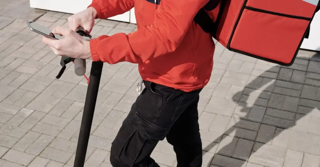 Repartidor usando su celular sobre un scooter en la ciudad