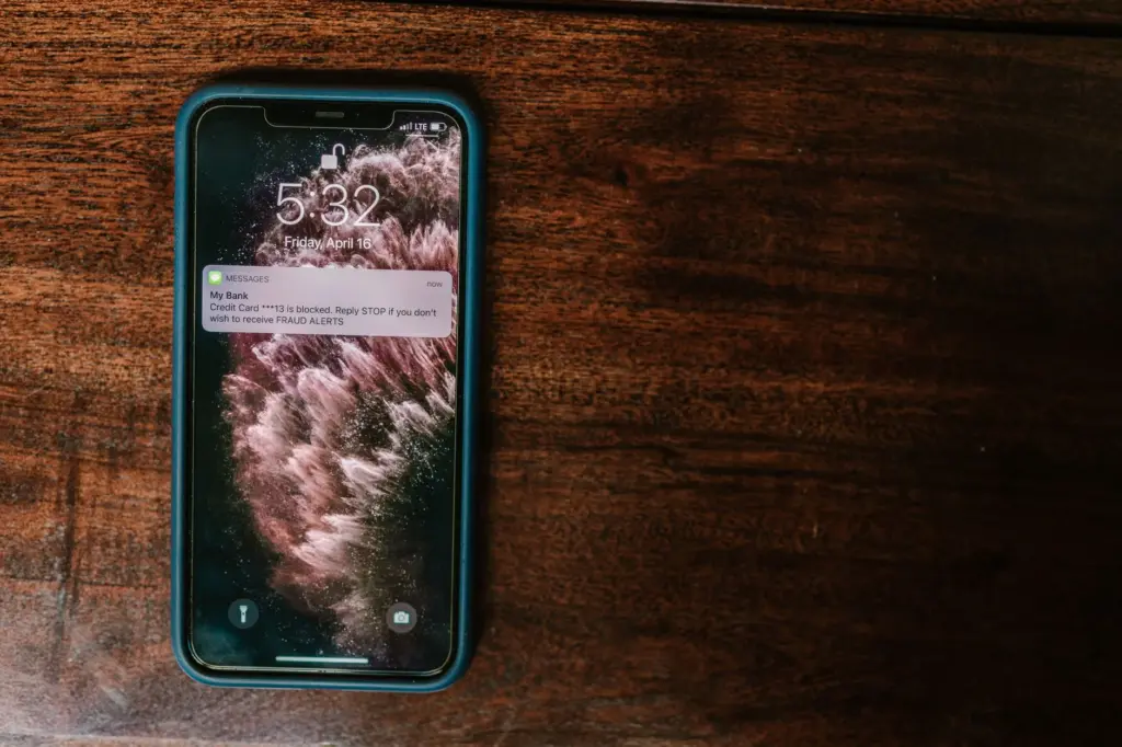 Celular sobre una superficie de madera mostrando una alerta