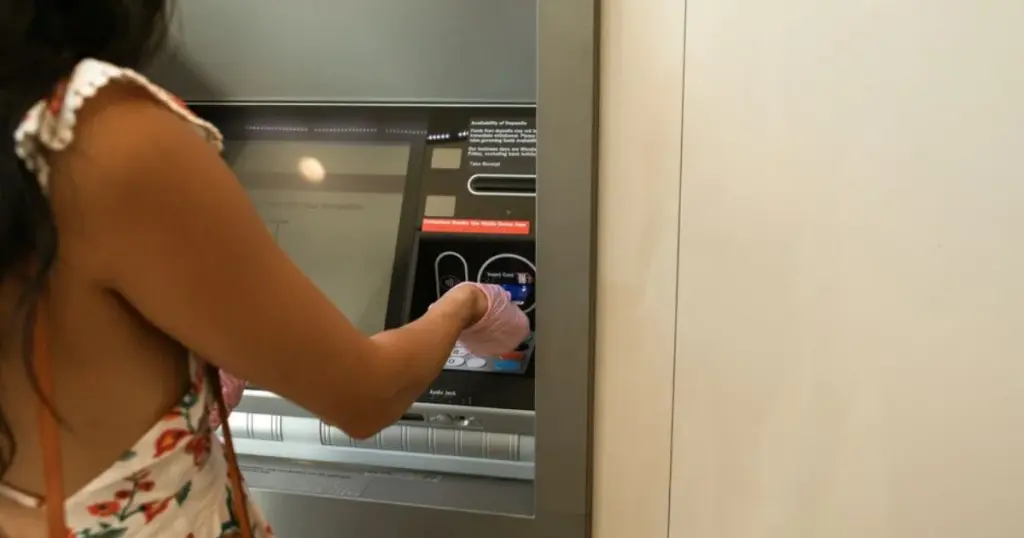Mujer usando un cajero automático para retirar dinero en el banco