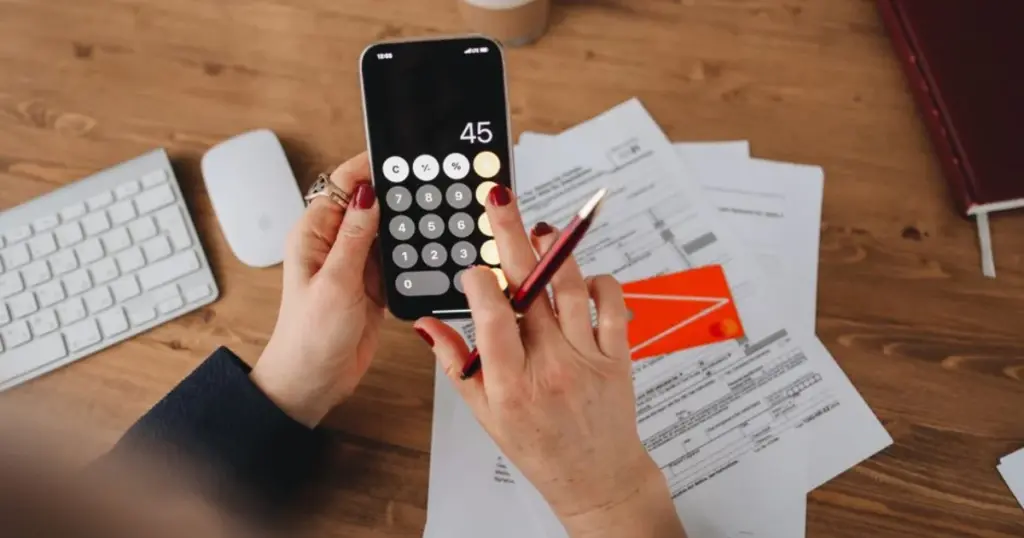 Persona calculando su presupuesto mientras revisa el celular