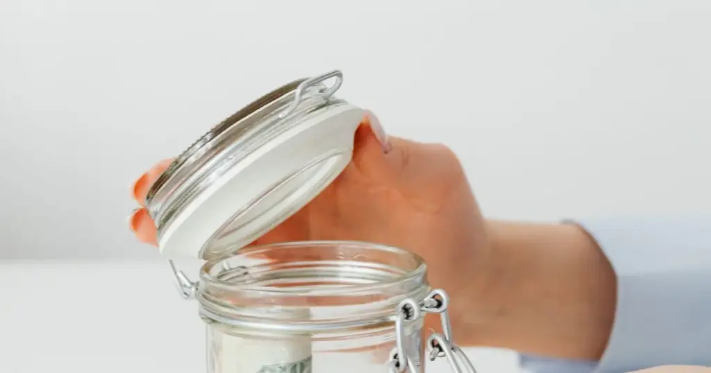 Persona ahorrando dinero en un frasco