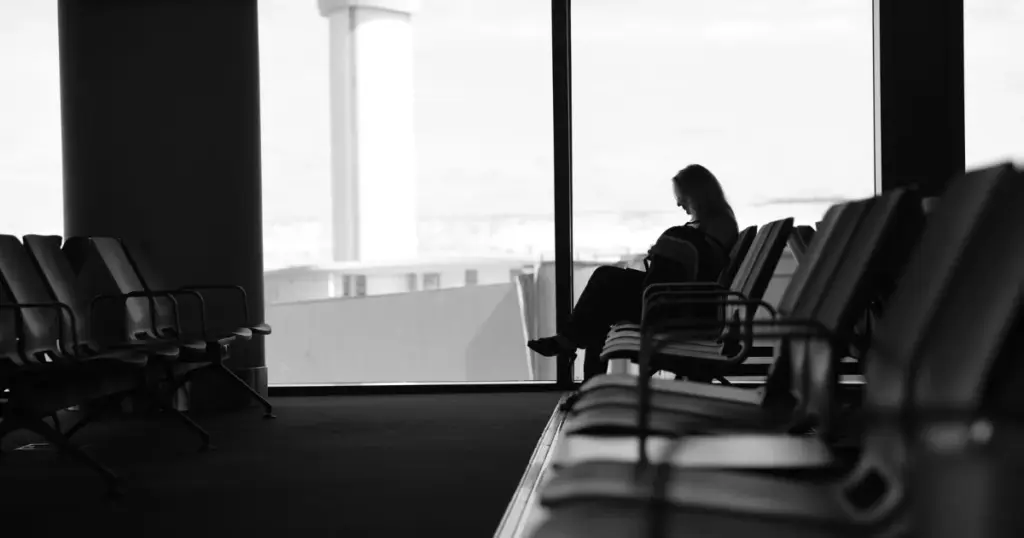 Persona esperando en una sala de espera de aeropuerto junto a la ventana