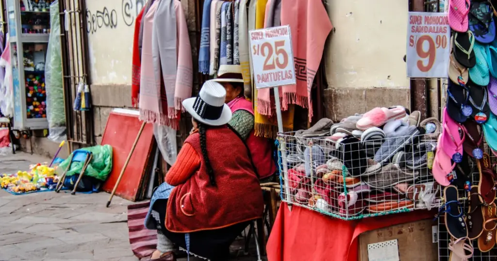 Mercado callejero en Perú con vendedores y productos, representando el trabajo informal y los ingresos bajos