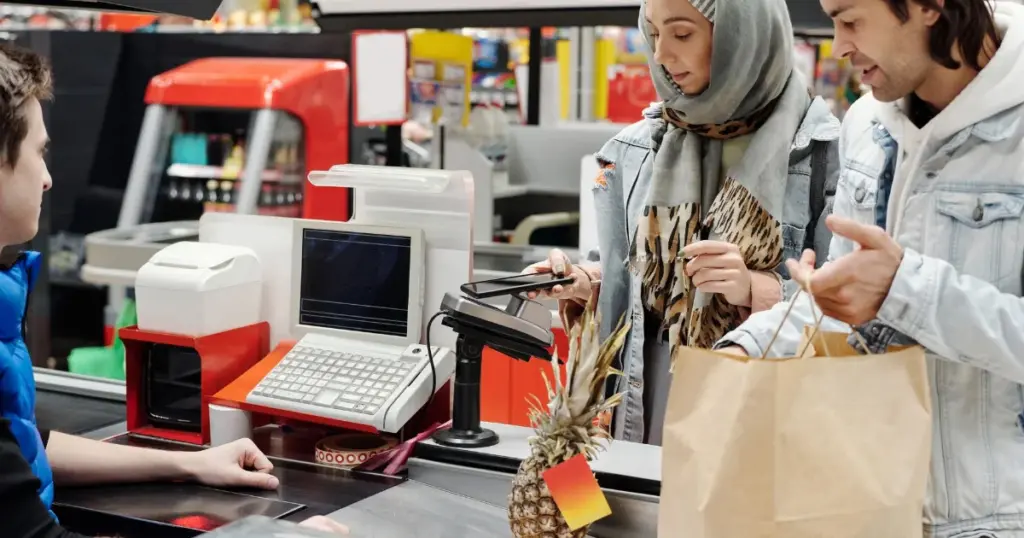 Pareja pagando con celular por QR en la caja de una tienda