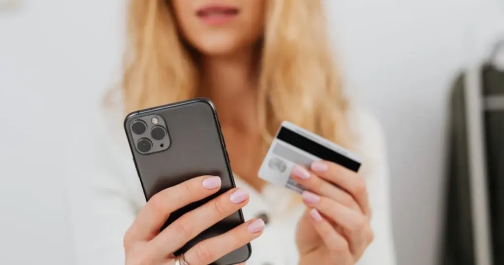 Mujer peruana revisando su tarjeta de crédito y celular