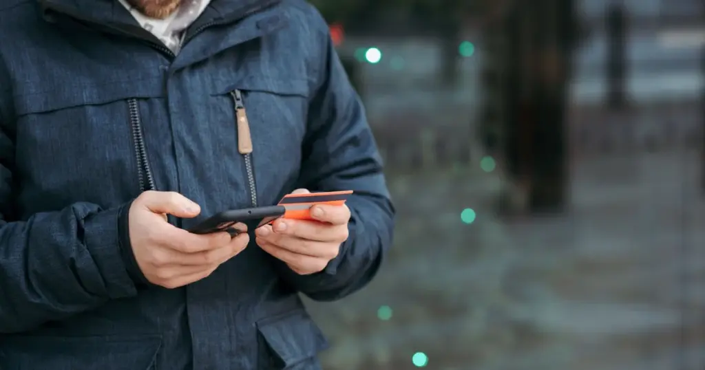 Persona ingresando datos de tarjeta en su celular en la calle