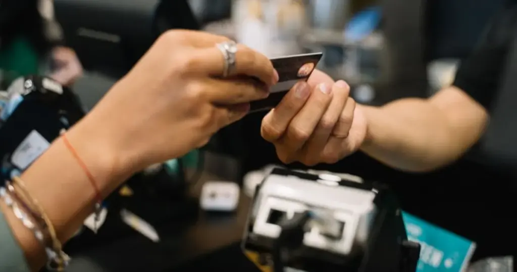 Cliente entregando tarjeta de crédito para pagar en una tienda, ejemplo de compra con cashback