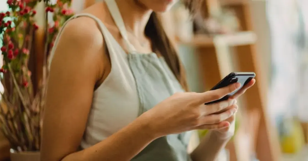 Trabajadora independiente peruana revisando su celular en su pequeño negocio