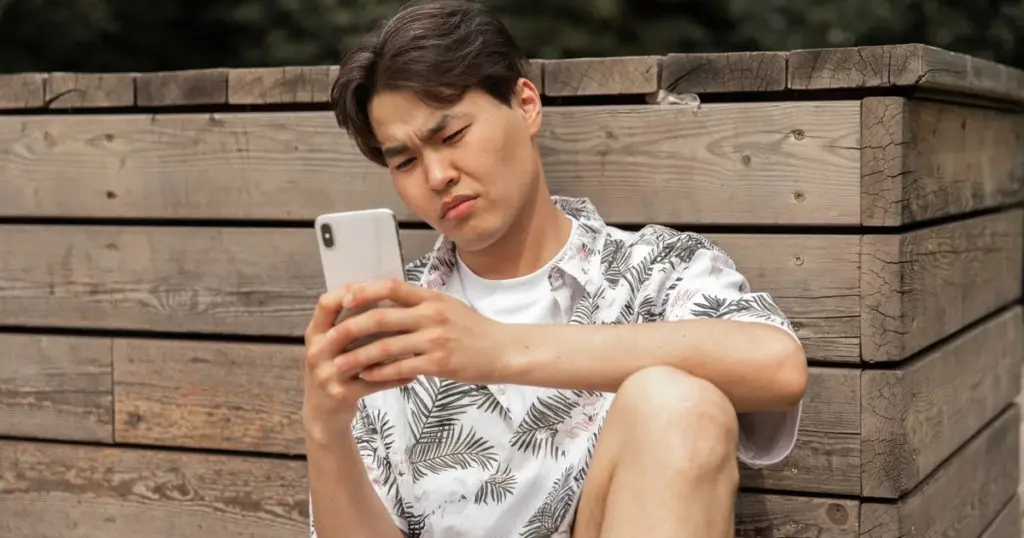 Hombre mirando su celular con expresión de duda ante una oferta