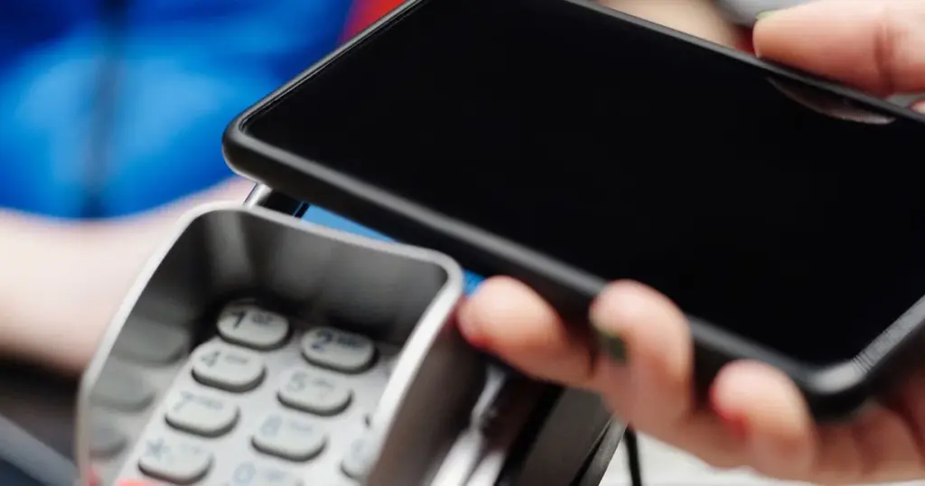 Persona pagando con celular y tarjeta en tienda