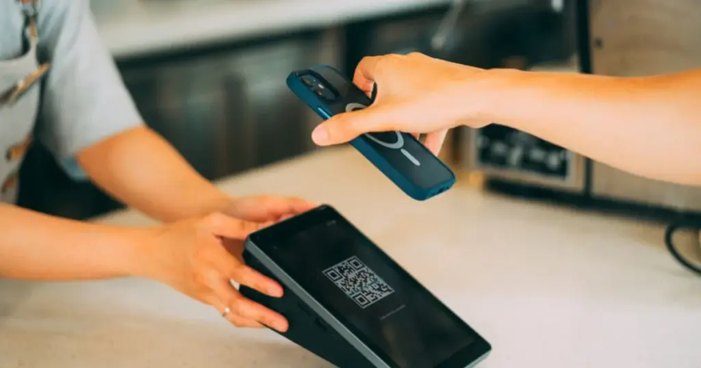 Persona escaneando un código QR con el celular para pagar