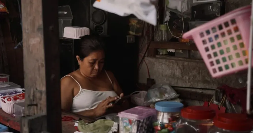 Mujer emprendedora usando su celular dentro de su pequeña tienda