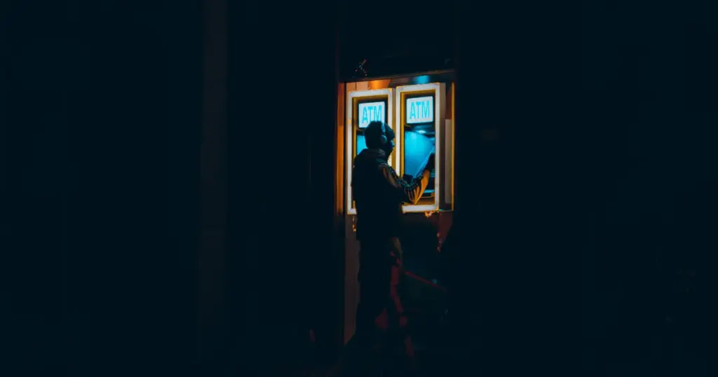 Persona retirando efectivo en un cajero automático de noche