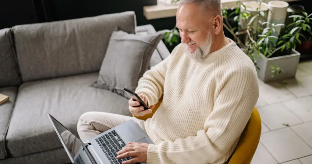 Hombre usando el teléfono y la laptop al mismo tiempo