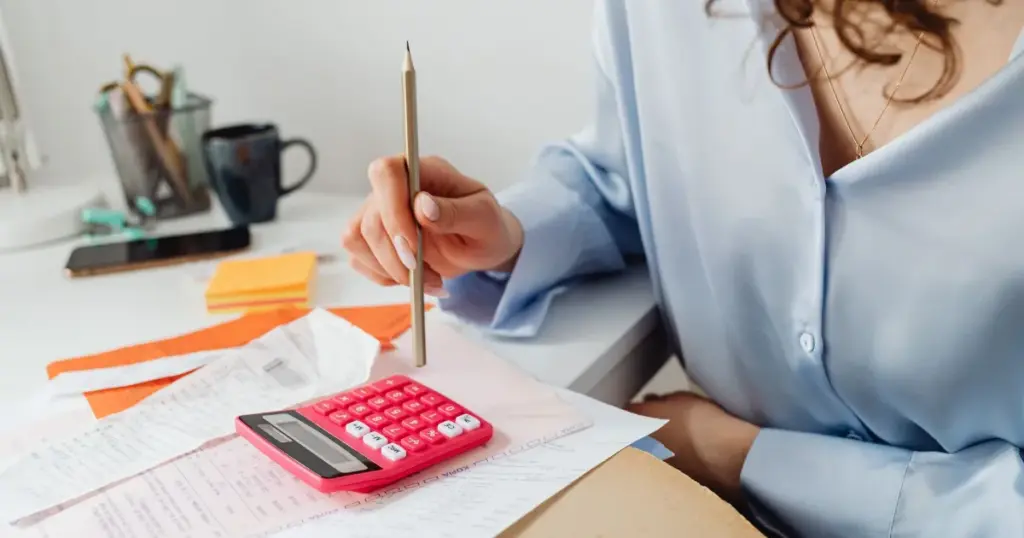 Mujer calculando ingresos con calculadora y recibos